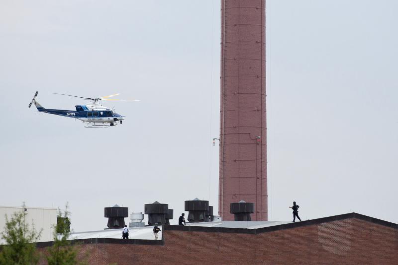 A police helicopter flies overhead as officers walk on the roof of a building. A police helicopter flies overhead as officers walk on the roof of a building.