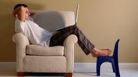 Man sitting on a club chair reading from his laptop. Man sitting on a club chair reading from his laptop.