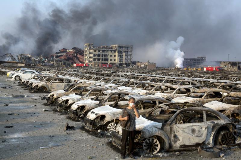 A man stands near the charred remains of new cars at a parking lot near the site of an explosion at a warehouse in northeastern China's Tianjin municipality. A man stands near the charred remains of new cars at a parking lot near the site of an explosion at a warehouse in northeastern China's Tianjin municipality.