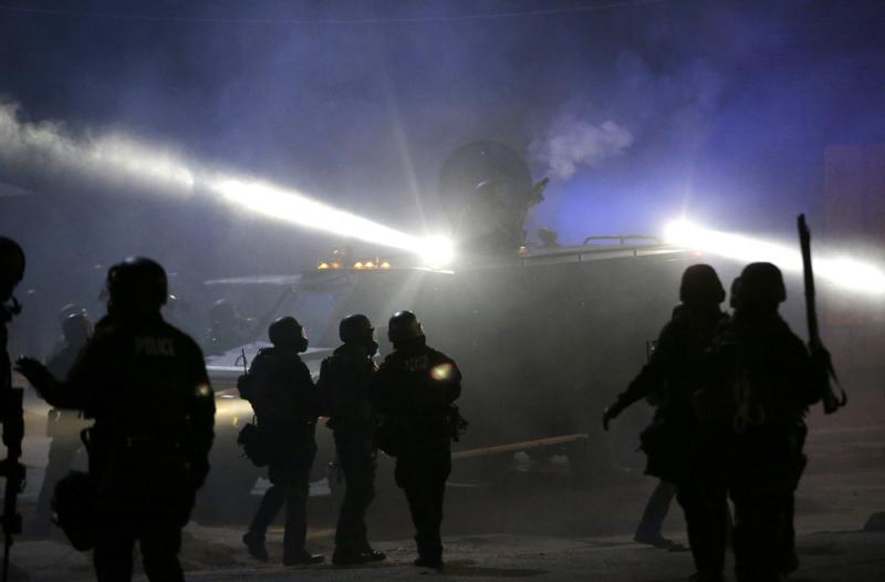 Police in riot gear stand around an armored vehicle as smoke fills the streets of Ferguson, Mo., in November 2014. Police in riot gear stand around an armored vehicle as smoke fills the streets of Ferguson, Mo., in November 2014.