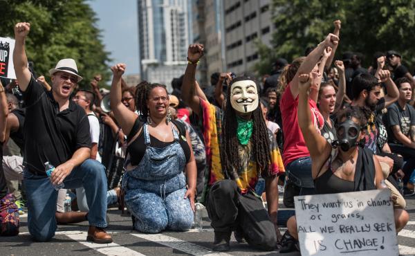 Demonstrators take a knee during the national anthem outside Bank of America Stadium before an NFL football game between the Carolina Panthers and the Minnesota Vikings on Sunday in Charlotte, N.C. Protests have disrupted the city since Tuesday night, fol Demonstrators take a knee during the national anthem outside Bank of America Stadium before an NFL football game between the Carolina Panthers and the Minnesota Vikings on Sunday in Charlotte, N.C. Protests have disrupted the city since Tuesday night, fol
