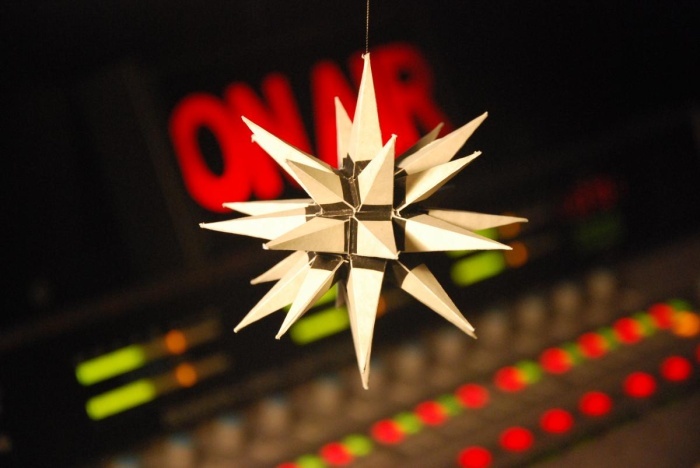 A Moravian star is suspended above and in front of a studio sound board.