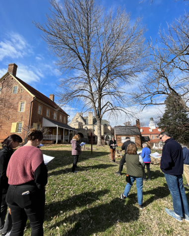 Listeners stand in front of brick buildings in Old Salem