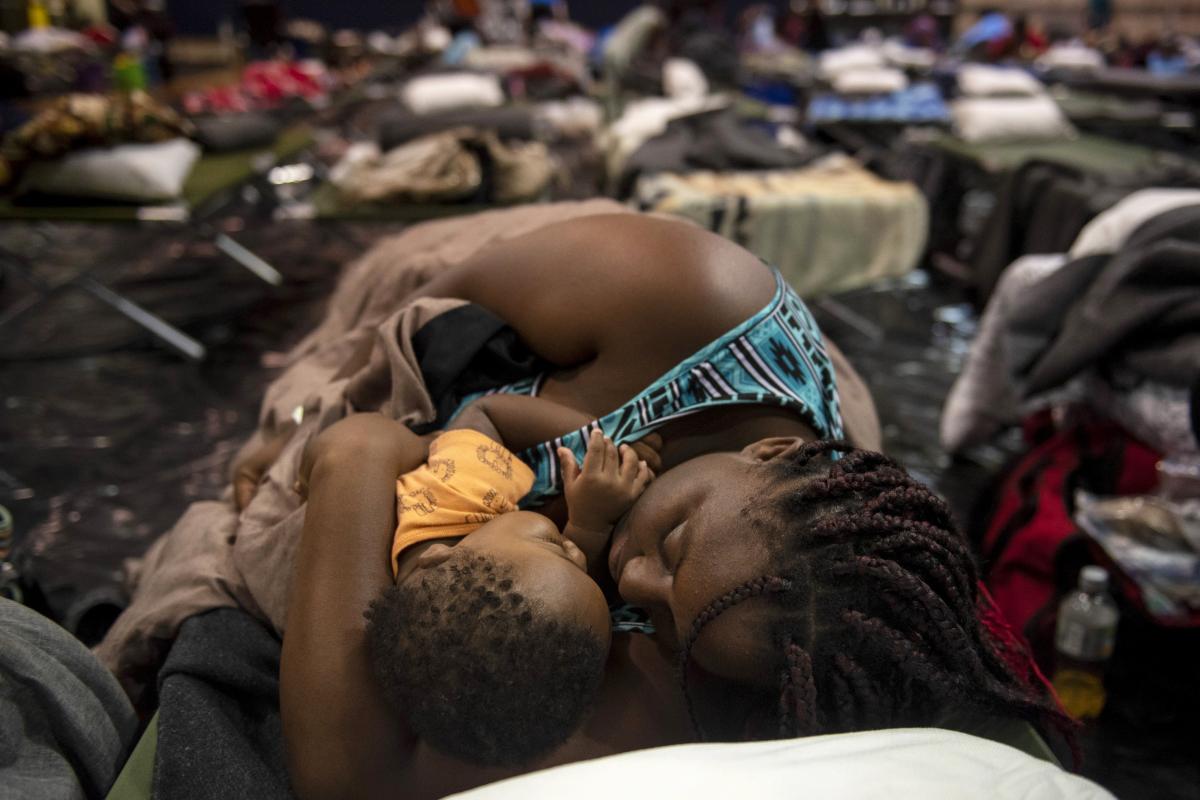 A woman holding a child sleeps after being evacuated at Southeast Raleigh High School ahead of Hurricane Florence in Raleigh N.C. on Wednesday