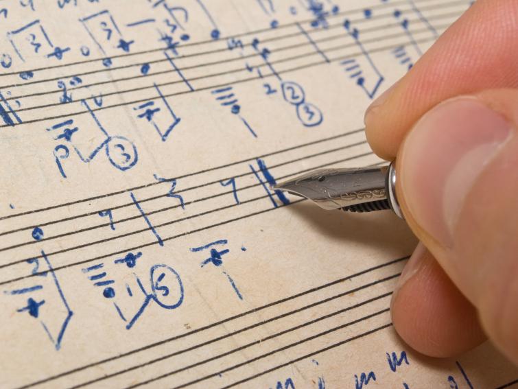 A hand writes music. A hand writes music.