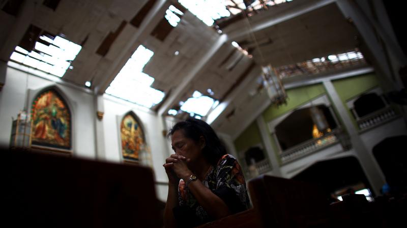 A Filipino woman prays at morning Mass at Santo Nino church, which was damaged by Typhoon Haiyan in Tacloban, Philippines, on Sunday. A Filipino woman prays at morning Mass at Santo Nino church, which was damaged by Typhoon Haiyan in Tacloban, Philippines, on Sunday.