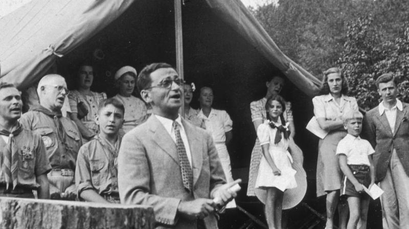 American composer Irving Berlin sings his song "God Bless America" in front of Boy Scouts troop members and spectators gathered at a tent in Monticello, New York in 1940. Instead of collecting royalties from "God Bless America," Berlin created a fund that American composer Irving Berlin sings his song "God Bless America" in front of Boy Scouts troop members and spectators gathered at a tent in Monticello, New York in 1940. Instead of collecting royalties from "God Bless America," Berlin created a fund that