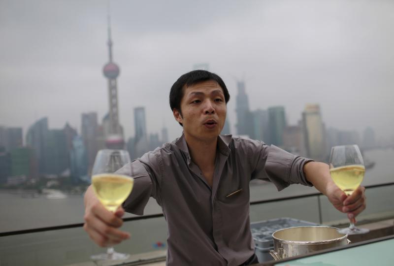 A waiter delivers glasses of wine to guests at a luxury hotel bar near the Bund in Shanghai, on Sept. 8, 2012. A waiter delivers glasses of wine to guests at a luxury hotel bar near the Bund in Shanghai, on Sept. 8, 2012.