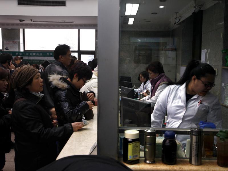 People wait in line at a counter for medical services at the Guanganmen Chinese medicine hospital in Beijing. People wait in line at a counter for medical services at the Guanganmen Chinese medicine hospital in Beijing.