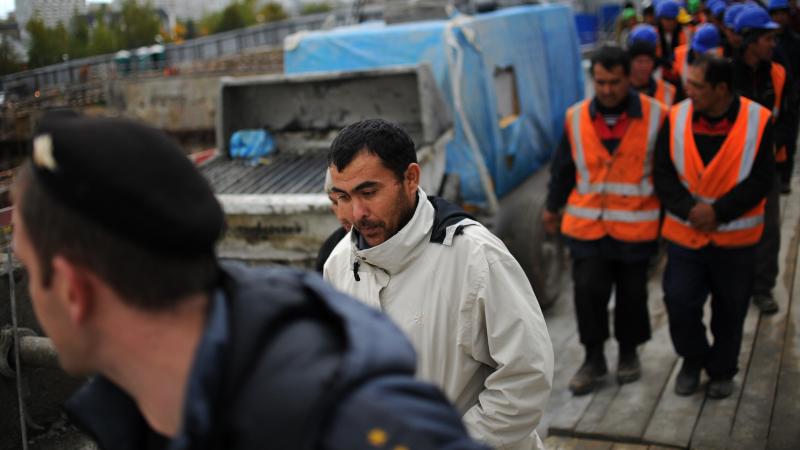 Migrant workers follow a police officer during a raid by Russian immigration authorities at a construction site in Moscow, in 2012. Migrant workers follow a police officer during a raid by Russian immigration authorities at a construction site in Moscow, in 2012.