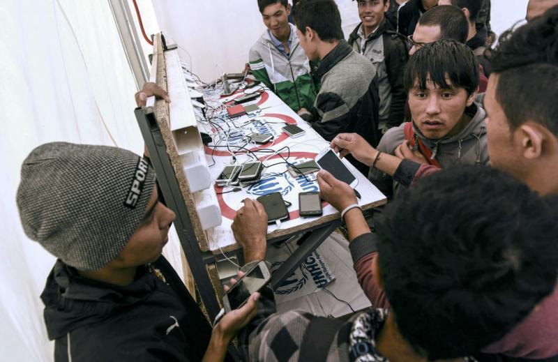 Migrants and asylum seekers charge their mobile phones at the registration camp after crossing the Macedonian-Greek border near Gevgelija on September 30, 2015. Macedonia is a key transit country in the Balkans migration route into the EU, with thousands