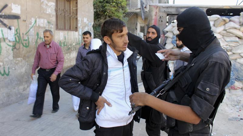 A Syrian fighter from the Islamist rebel group Jabhat al-Nusra inspects a resident's identification papers at a checkpoint in Aleppo on Oct. 26. Syria's Islamist fighters are generally better funded than their more moderate counterparts. A Syrian fighter from the Islamist rebel group Jabhat al-Nusra inspects a resident's identification papers at a checkpoint in Aleppo on Oct. 26. Syria's Islamist fighters are generally better funded than their more moderate counterparts.
