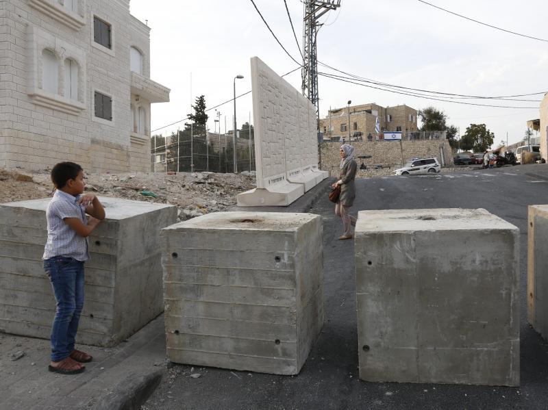 Palestinians look at a new concrete wall erected by Israeli security forces in the East Jerusalem neighborhood of Jabel Mukaber. Palestinians look at a new concrete wall erected by Israeli security forces in the East Jerusalem neighborhood of Jabel Mukaber.