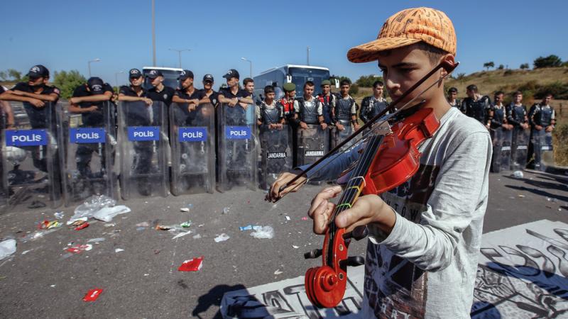 A refugee boy plays a violin as hundreds of migrants are blocked from marching down a highway toward Turkey's western border with Greece and Bulgaria on Saturday. Turkey has some 2 million refugees, mostly from Syria, but says they will not be allowed to A refugee boy plays a violin as hundreds of migrants are blocked from marching down a highway toward Turkey's western border with Greece and Bulgaria on Saturday. Turkey has some 2 million refugees, mostly from Syria, but says they will not be allowed to
