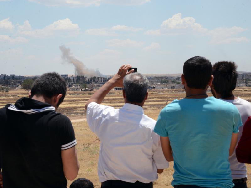 Turkish Kurds watch from the Turkish side of the border Friday as smoke rises in Kobani, Syria. Since last year, the town has seen control seesaw between Kurds and Islamic State militants. Turkish Kurds watch from the Turkish side of the border Friday as smoke rises in Kobani, Syria. Since last year, the town has seen control seesaw between Kurds and Islamic State militants.