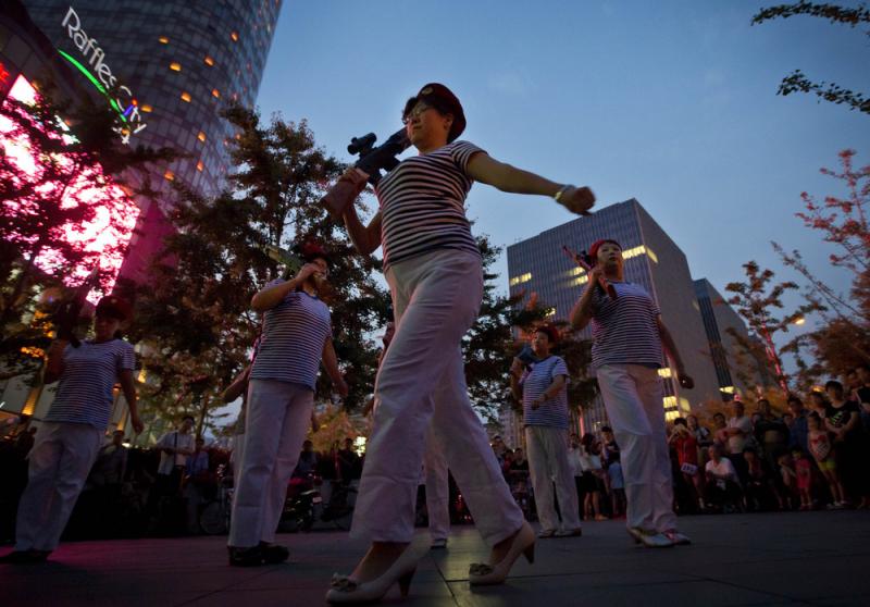 Chinese women holding toy guns dance to a revolutionary song during their daily exercises at a square outside a shopping mall in Beijing. The Chinese government is beginning to regulate public square-dancing, after the practice drew complaints about noise Chinese women holding toy guns dance to a revolutionary song during their daily exercises at a square outside a shopping mall in Beijing. The Chinese government is beginning to regulate public square-dancing, after the practice drew complaints about noise