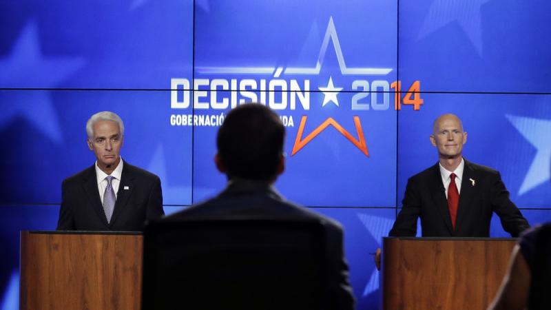 Democrat Charlie Crist, a former Republican governor of Florida (left), and Rick Scott, the current Republican governor of Florida, listen to the moderators during a gubernatorial debate on Friday. The two are facing off in a tight race that's fueling a b Democrat Charlie Crist, a former Republican governor of Florida (left), and Rick Scott, the current Republican governor of Florida, listen to the moderators during a gubernatorial debate on Friday. The two are facing off in a tight race that's fueling a b