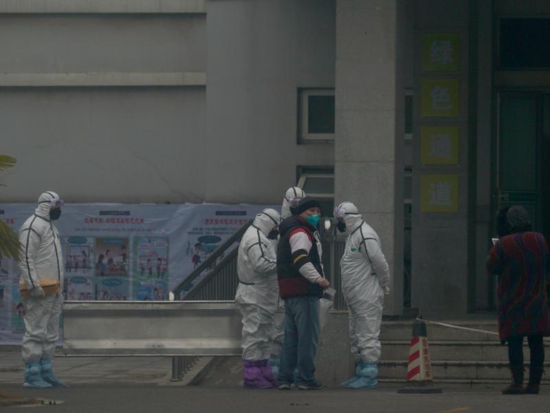 Staff in biohazard suits hold a metal stretcher on Tuesday by the inpatient department of Wuhan Medical Treatment Center, where some people infected with a novel coronavirus are being treated in China. Staff in biohazard suits hold a metal stretcher on Tuesday by the inpatient department of Wuhan Medical Treatment Center, where some people infected with a novel coronavirus are being treated in China.
