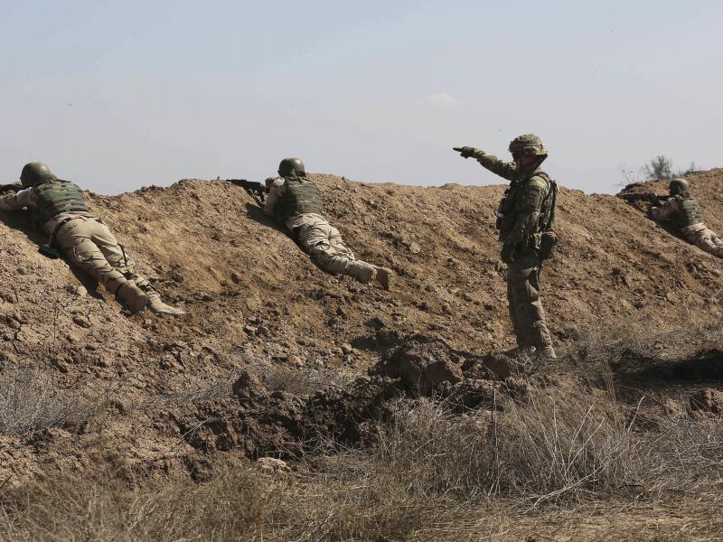 A U.S. soldier (standing) helps Iraqi security forces improve shooting skills at Camp Taji, north of Baghdad, in 2015. A U.S. soldier (standing) helps Iraqi security forces improve shooting skills at Camp Taji, north of Baghdad, in 2015.