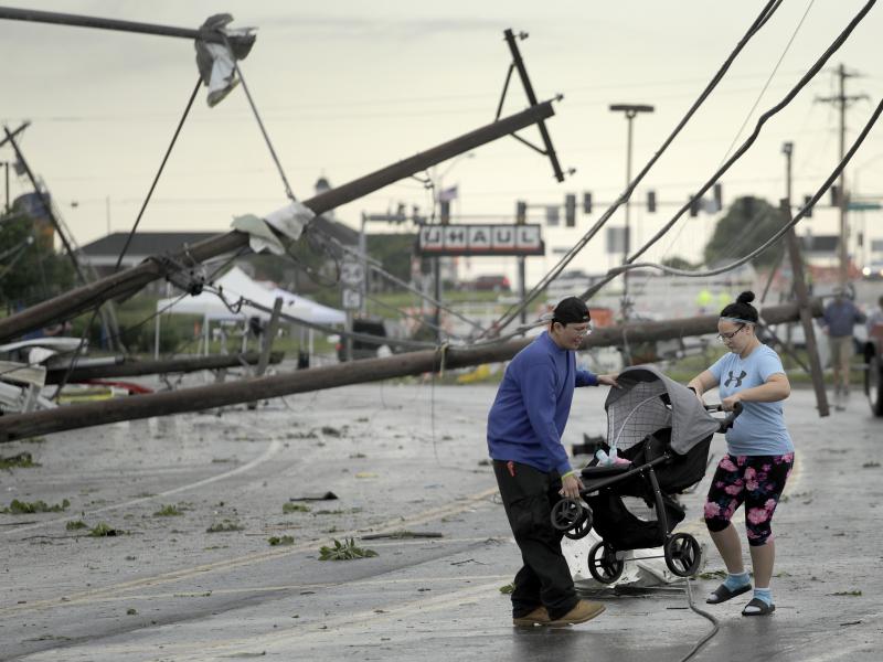 Jessica Rodgers and neighbor Ray Arellana carry a stroller carrying Rodgers' sister Sophia Rodgers over downed power lines as they head to Rodgers' mother's apartment to check on damage on Thursday after a tornado tore though Jefferson City, Mo., late Wed Jessica Rodgers and neighbor Ray Arellana carry a stroller carrying Rodgers' sister Sophia Rodgers over downed power lines as they head to Rodgers' mother's apartment to check on damage on Thursday after a tornado tore though Jefferson City, Mo., late Wed