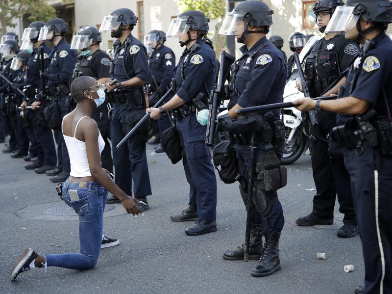 A masked protester kneels before San Jose police in San Jose, Calif. last month. Four officers have been placed on administrative leave after allegations that they posted racist and anti-Muslim messages to social media. A masked protester kneels before San Jose police in San Jose, Calif. last month. Four officers have been placed on administrative leave after allegations that they posted racist and anti-Muslim messages to social media.