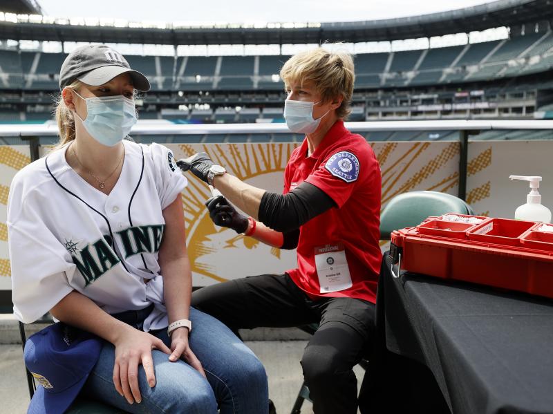 Sydney Porter of Bellevue, Wash., receives her COVID-19 vaccination from Kristine Gill, with the Seattle Fire Department's Mobile Vaccination Teams, before the game between the Seattle Mariners and the Baltimore Orioles at T-Mobile Park on May 5 in Seattl Sydney Porter of Bellevue, Wash., receives her COVID-19 vaccination from Kristine Gill, with the Seattle Fire Department's Mobile Vaccination Teams, before the game between the Seattle Mariners and the Baltimore Orioles at T-Mobile Park on May 5 in Seattl