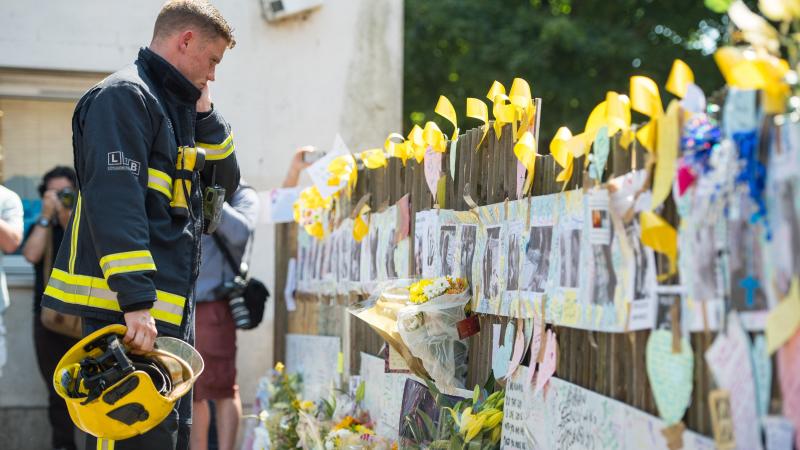 A firefighter looks at tributes to presumed victims of the Grenfell Tower fire, after observing a minute's silence at a community center near the apartment building in west London. A firefighter looks at tributes to presumed victims of the Grenfell Tower fire, after observing a minute's silence at a community center near the apartment building in west London.