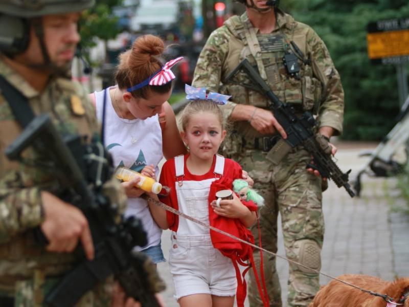 Law enforcement escorts a family away from the scene of a shooting at a parade on July 4 in Highland Park, Ill. Law enforcement escorts a family away from the scene of a shooting at a parade on July 4 in Highland Park, Ill.
