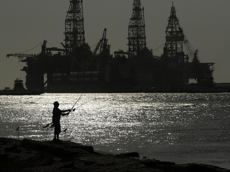 A man wears a face mark as he fishes near docked oil drilling platforms, Friday, May 8, 2020, in Port Aransas, Texas. A man wears a face mark as he fishes near docked oil drilling platforms, Friday, May 8, 2020, in Port Aransas, Texas.