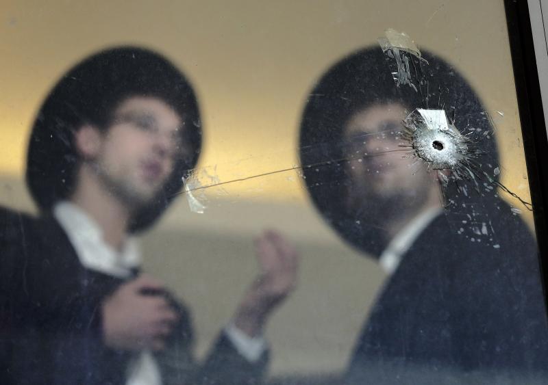 Ultra Orthodox Jews look at bullet holes in the main window of a synagogue in Jerusalem on Wednesday. Ultra Orthodox Jews look at bullet holes in the main window of a synagogue in Jerusalem on Wednesday.