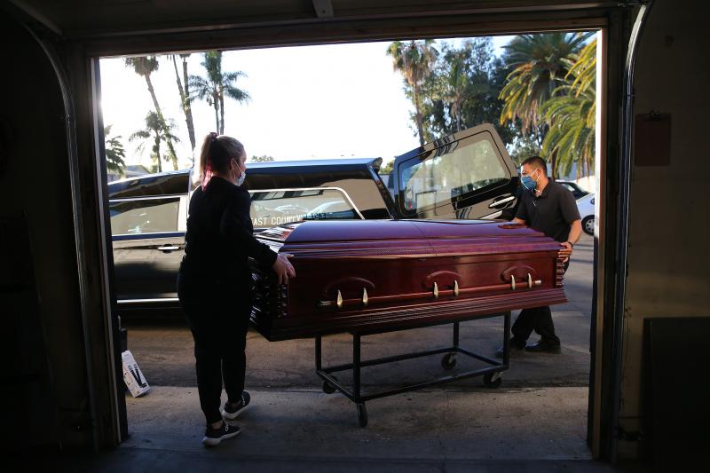 Embalmer and funeral director Kristy Oliver (left) and funeral attendant Sam Deras load the casket of a person who died after contracting COVID-19 into a hearse in El Cajon, Calif. People who work in hospitals and in funeral homes are witnesses to the los Embalmer and funeral director Kristy Oliver (left) and funeral attendant Sam Deras load the casket of a person who died after contracting COVID-19 into a hearse in El Cajon, Calif. People who work in hospitals and in funeral homes are witnesses to the los