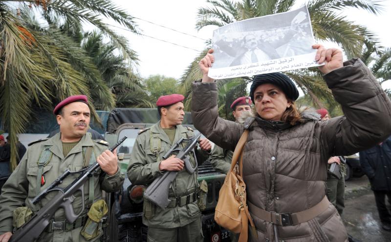 Tunisian soldiers stand guard as a woman holds up a poster featuring opposition leader Chokri Belaid during his funeral procession in a suburb of Tunis on Feb. 8. Belaid's assassination has laid bare the political rifts in post-revolutionary Tunisia. Tunisian soldiers stand guard as a woman holds up a poster featuring opposition leader Chokri Belaid during his funeral procession in a suburb of Tunis on Feb. 8. Belaid's assassination has laid bare the political rifts in post-revolutionary Tunisia.