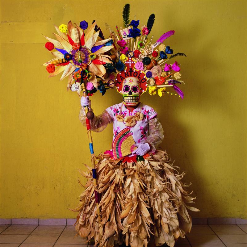 This costume, with corn husks and feathers and paper flowers, is worn by a member of a dance group that gathers in cemeteries and other places to mark Day of the Dead festivities (called Xantolo, the word written above the mask). The idea of combining a s This costume, with corn husks and feathers and paper flowers, is worn by a member of a dance group that gathers in cemeteries and other places to mark Day of the Dead festivities (called Xantolo, the word written above the mask). The idea of combining a s