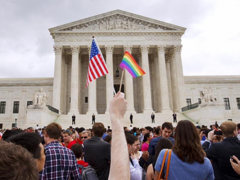 A man holds a U.S. and a rainbow flag outside the Supreme Court in Washington, D.C., on June 26, 2015, after the court legalized gay marriage nationwide. A man holds a U.S. and a rainbow flag outside the Supreme Court in Washington, D.C., on June 26, 2015, after the court legalized gay marriage nationwide.