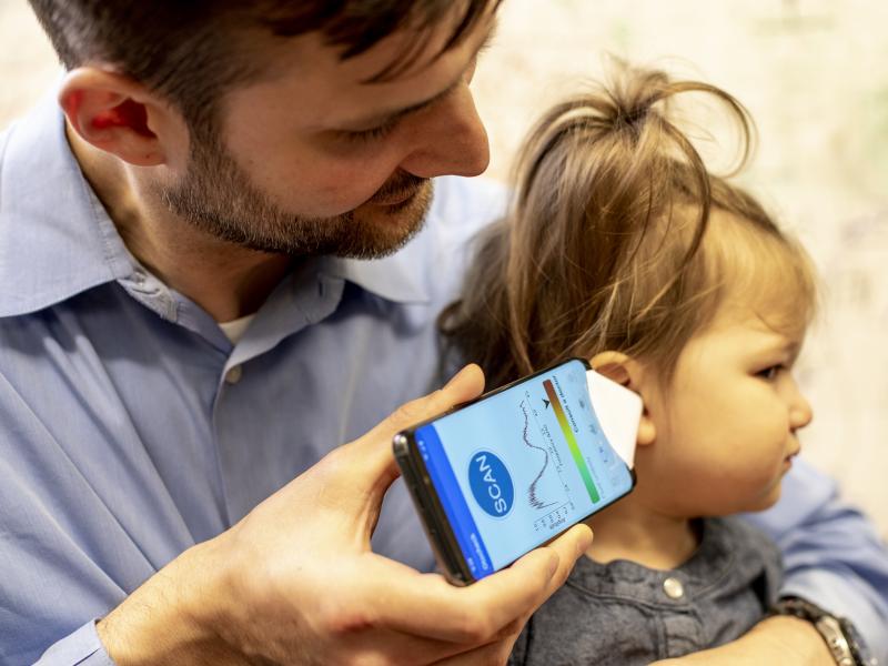 Dr. Randall Bly, an assistant professor of otolaryngology-head and neck surgery at the University of Washington School of Medicine who practices at Seattle Children's Hospital, uses the experimental smartphone app and a paper funnel to check his daughter' Dr. Randall Bly, an assistant professor of otolaryngology-head and neck surgery at the University of Washington School of Medicine who practices at Seattle Children's Hospital, uses the experimental smartphone app and a paper funnel to check his daughter'