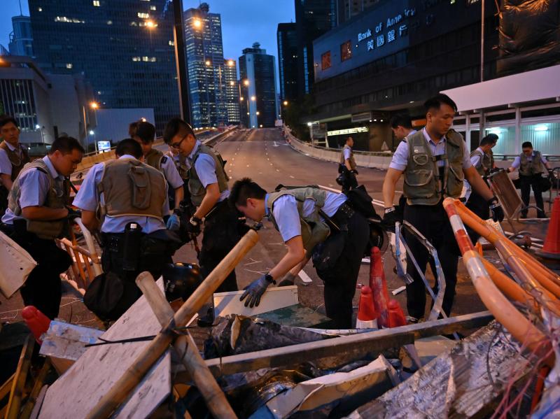 Police officers on Thursday dismantle barricades placed earlier by demonstrators in Hong Kong. Police officers on Thursday dismantle barricades placed earlier by demonstrators in Hong Kong.