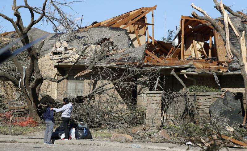 Women stand outside a house damaged by a tornado Sunday night in the Preston Hollow section of Dallas. The city was still cleaning up on Monday. Women stand outside a house damaged by a tornado Sunday night in the Preston Hollow section of Dallas. The city was still cleaning up on Monday.