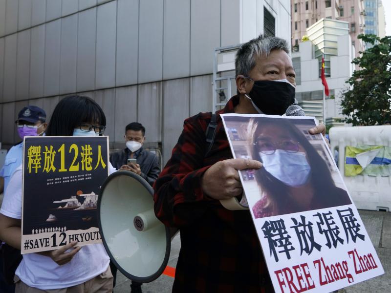 Pro-democracy activists (right) hold placards with the picture of Chinese citizen journalist Zhang Zhan as they march to the Chinese central government's liaison office in Hong Kong in Dec. 2020. Pro-democracy activists (right) hold placards with the picture of Chinese citizen journalist Zhang Zhan as they march to the Chinese central government's liaison office in Hong Kong in Dec. 2020.