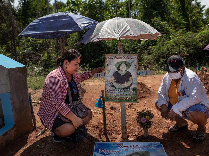 Margarita Ahuanari, left, and Karina Ahuanari look at posters of their mother. The images were placed where they think she was buried at the mass grave that was later renamed the COVID-19 Cemetery in Iquitos. Margarita Ahuanari, left, and Karina Ahuanari look at posters of their mother. The images were placed where they think she was buried at the mass grave that was later renamed the COVID-19 Cemetery in Iquitos.