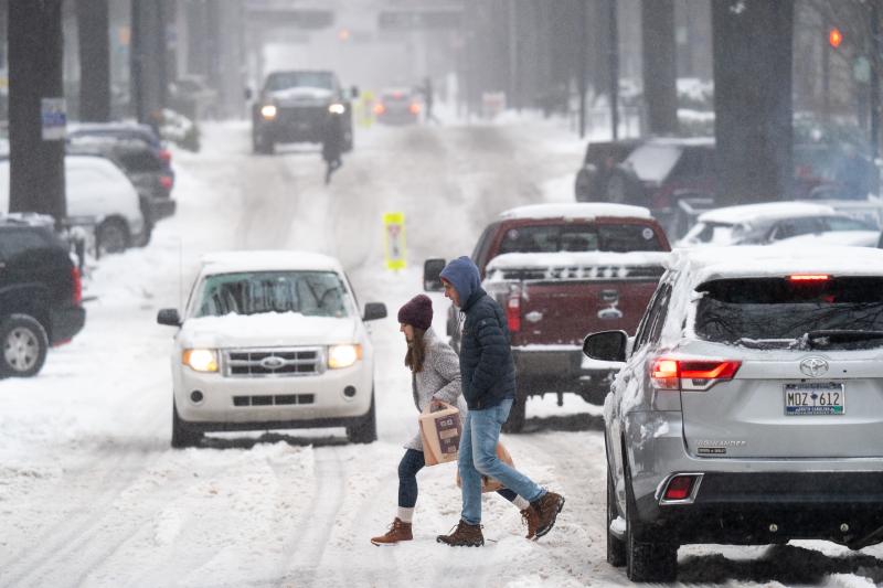 Pedestrians cross a street as motorists drive through the snow on Jan. 16 in Greenville, S.C. Pedestrians cross a street as motorists drive through the snow on Jan. 16 in Greenville, S.C.