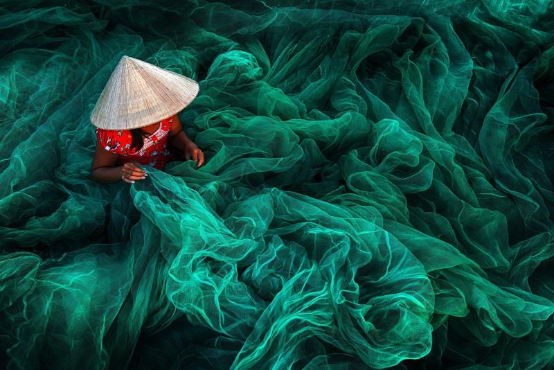In a village in southern Vietnam, a woman weaves a fishing net. By tradition, Vietnamese women make nets for their husbands. In a village in southern Vietnam, a woman weaves a fishing net. By tradition, Vietnamese women make nets for their husbands.