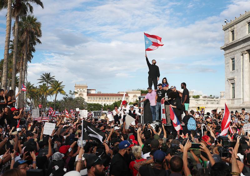Bad Bunny (holding flag), singer Ricky Martin (in black hat) and Residente (in blue hat) join demonstrators in protest against Puerto Rico Gov. Ricardo Rosselló in Old San Juan. Bad Bunny (holding flag), singer Ricky Martin (in black hat) and Residente (in blue hat) join demonstrators in protest against Puerto Rico Gov. Ricardo Rosselló in Old San Juan.