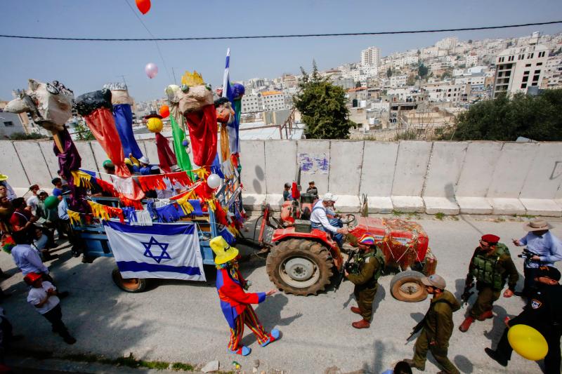 Israeli settlers celebrate the Jewish Purim holiday on al-Shuhada Street in the divided West Bank town of Hebron on March 21. Israeli settlers celebrate the Jewish Purim holiday on al-Shuhada Street in the divided West Bank town of Hebron on March 21.