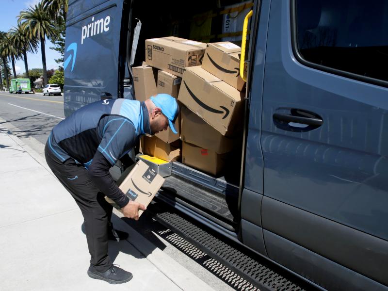 A driver picks up a package while making deliveries for Amazon in Costa Mesa, Calif., on March 23. Amazon is offering to permanent jobs for 125,000 workers it hired to deal with a sharp rise in online shopping during the coronavirus pandemic. A driver picks up a package while making deliveries for Amazon in Costa Mesa, Calif., on March 23. Amazon is offering to permanent jobs for 125,000 workers it hired to deal with a sharp rise in online shopping during the coronavirus pandemic.