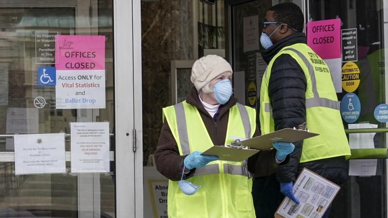 Workers are seen outside a city building in Milwaukee, which set up drive-up early voting for the state's April 7 election in response to the coronavirus outbreak. Workers are seen outside a city building in Milwaukee, which set up drive-up early voting for the state's April 7 election in response to the coronavirus outbreak.