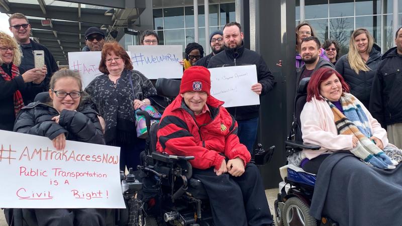 Members of the Illinois Network of Centers for Independent Living (INCIL) demonstrate in front of the Bloomington-Normal Amtrak station in Illinois to demand the suspension of an Amtrak policy that led to exorbitant fees for removing train seats to accomm Members of the Illinois Network of Centers for Independent Living (INCIL) demonstrate in front of the Bloomington-Normal Amtrak station in Illinois to demand the suspension of an Amtrak policy that led to exorbitant fees for removing train seats to accomm