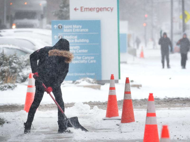 A worker shovels snow from a sidewalk in the Humboldt Park neighborhood of Chicago. Forecasters expect temperatures to drop around 10 degrees by Wednesday. A worker shovels snow from a sidewalk in the Humboldt Park neighborhood of Chicago. Forecasters expect temperatures to drop around 10 degrees by Wednesday.
