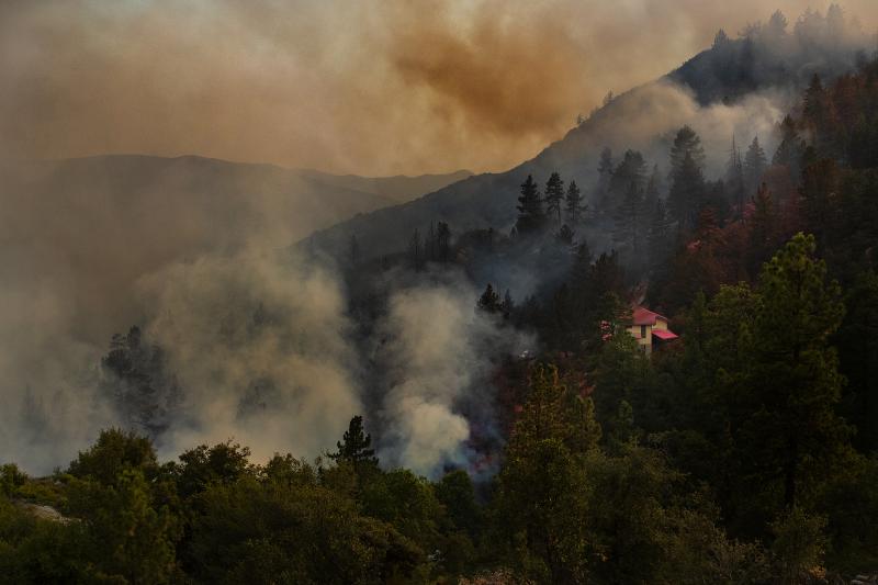 A house is covered in pink fire retardant as the Cranston Fire burns out of control near the town of Idyllwild in the San Bernardino National Forest on Wednesday. A house is covered in pink fire retardant as the Cranston Fire burns out of control near the town of Idyllwild in the San Bernardino National Forest on Wednesday.