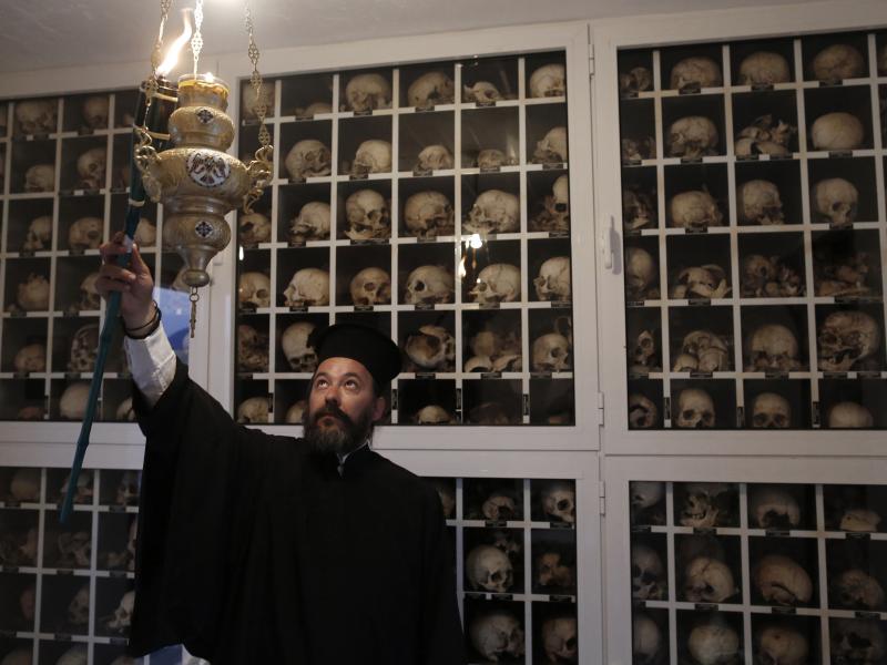 Greek Orthodox priest Apostolos Stavropoulos, 41, lights a torch inside the mausoleum in the village of Distomo in June 2013 on the eve of the 69th anniversary of the massacre committed by the Nazis during World War II. The remains of the more than 200 vi Greek Orthodox priest Apostolos Stavropoulos, 41, lights a torch inside the mausoleum in the village of Distomo in June 2013 on the eve of the 69th anniversary of the massacre committed by the Nazis during World War II. The remains of the more than 200 vi