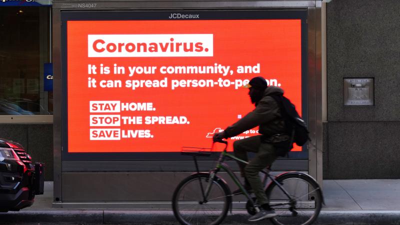 A person on a bike rides by a sign in New York City urging people to stay home in May. As the pandemic drags on, some workers are facing tough choices — balancing potential risks of unwittingly spreading the disease against the possibility of losing pay A person on a bike rides by a sign in New York City urging people to stay home in May. As the pandemic drags on, some workers are facing tough choices — balancing potential risks of unwittingly spreading the disease against the possibility of losing pay